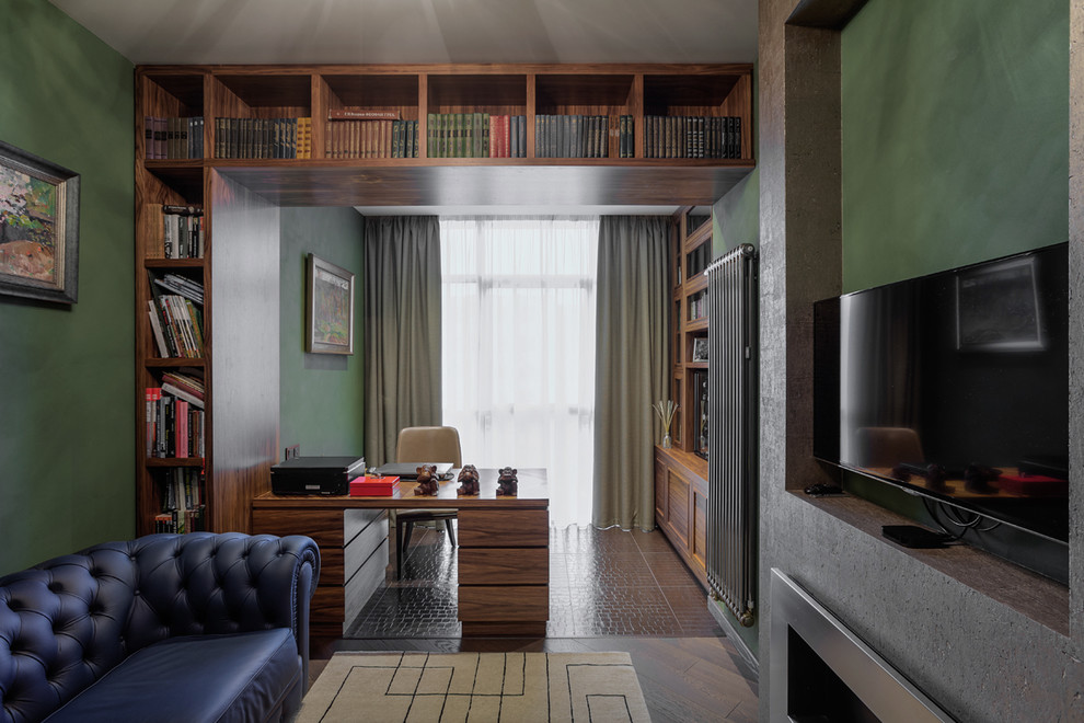 Foto de despacho actual con paredes verdes, chimenea lineal, marco de chimenea de metal y escritorio independiente