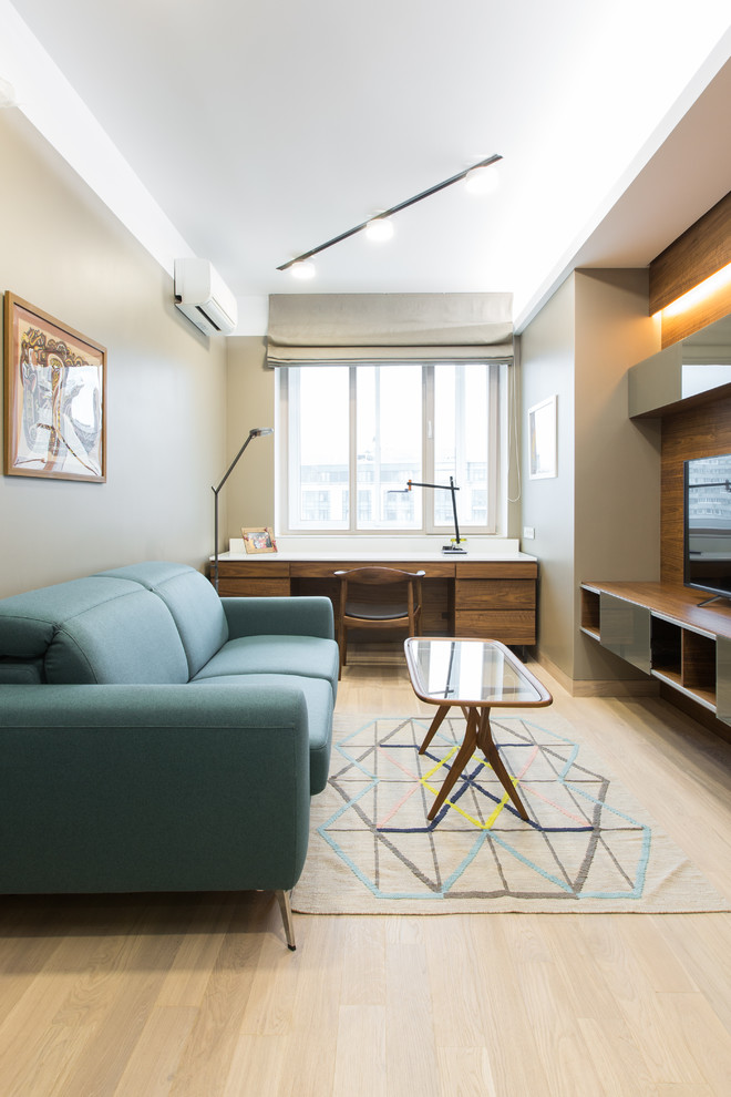 Ejemplo de despacho actual de tamaño medio con paredes grises, suelo de madera clara y escritorio empotrado