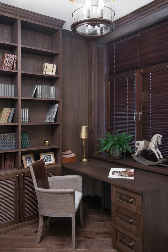 Foto på ett vintage hemmabibliotek, med bruna väggar, mörkt trägolv och ett inbyggt skrivbord