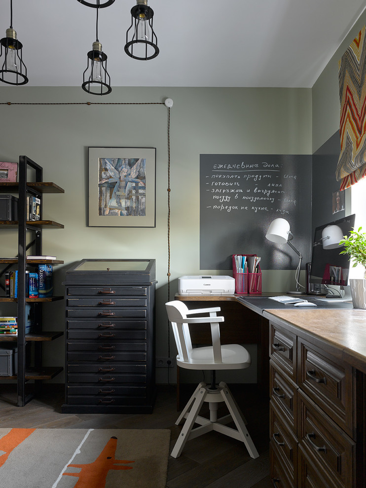 Diseño de despacho industrial con paredes verdes, suelo de madera oscura, escritorio independiente y suelo marrón