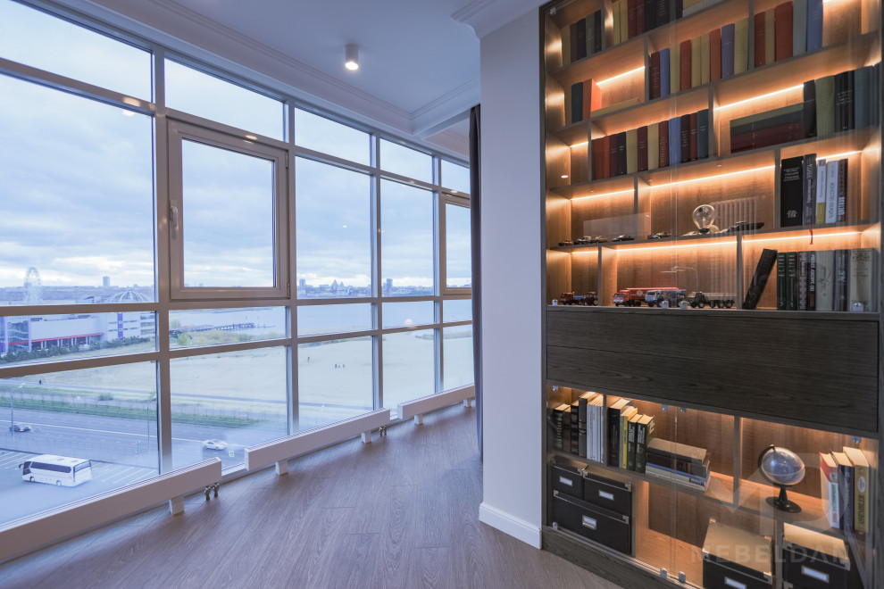 Diseño de despacho contemporáneo de tamaño medio con biblioteca, paredes blancas, suelo vinílico, escritorio independiente y suelo marrón