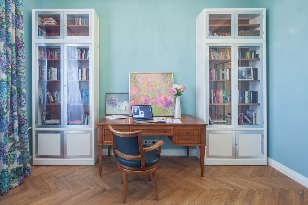 Klassisk inredning av ett mellanstort hemmabibliotek, med gröna väggar, mellanmörkt trägolv och ett fristående skrivbord