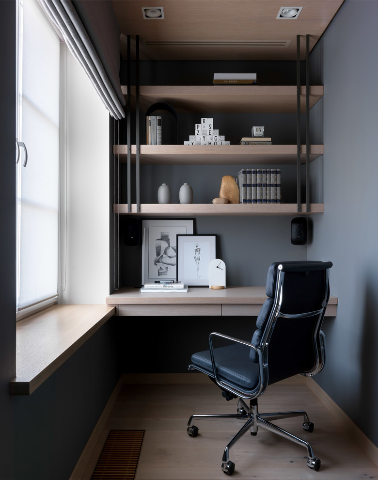 Modelo de despacho nórdico grande con paredes grises, suelo de madera clara, escritorio empotrado y suelo beige
