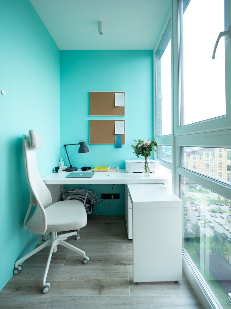 Idee per uno studio minimal di medie dimensioni con pareti blu, scrivania autoportante e pavimento grigio