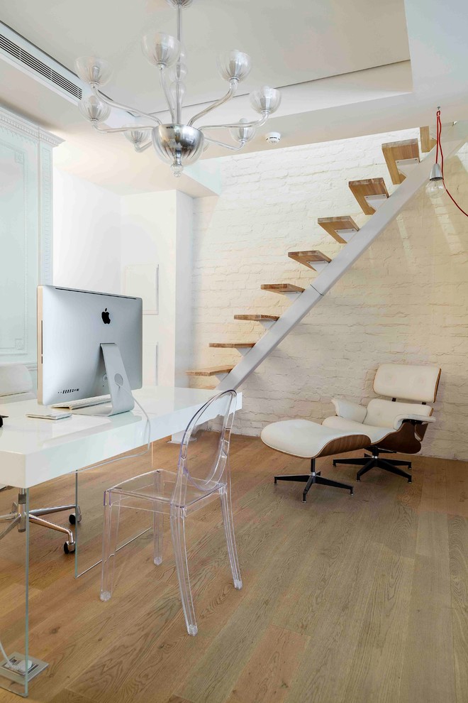 Bild på ett mellanstort industriellt hobbyrum, med vita väggar, ljust trägolv, ett fristående skrivbord och beiget golv