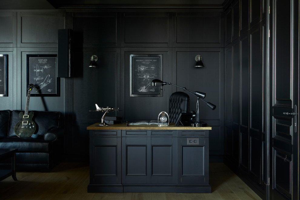 Klassisk inredning av ett hemmabibliotek, med svarta väggar, ett fristående skrivbord, ljust trägolv och beiget golv