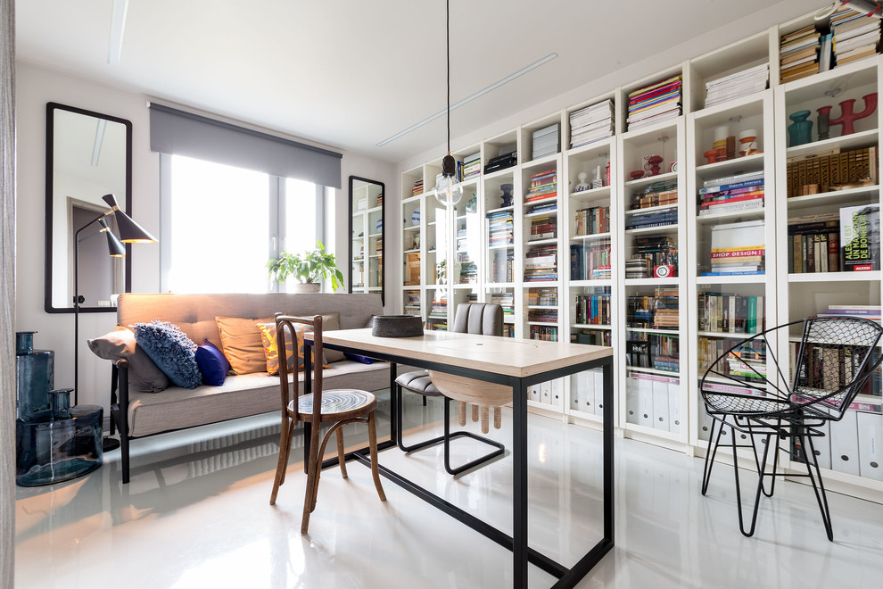 На фото: домашняя библиотека в скандинавском стиле с белым полом, серыми стенами и отдельно стоящим рабочим столом