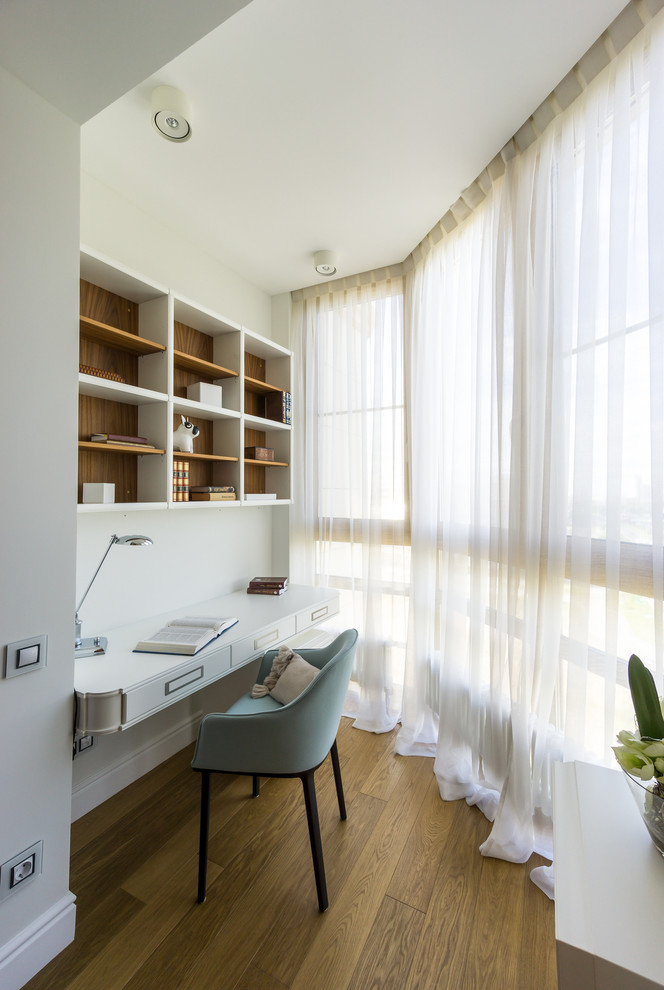 Ejemplo de despacho tradicional renovado sin chimenea con paredes blancas, suelo de madera en tonos medios y escritorio empotrado