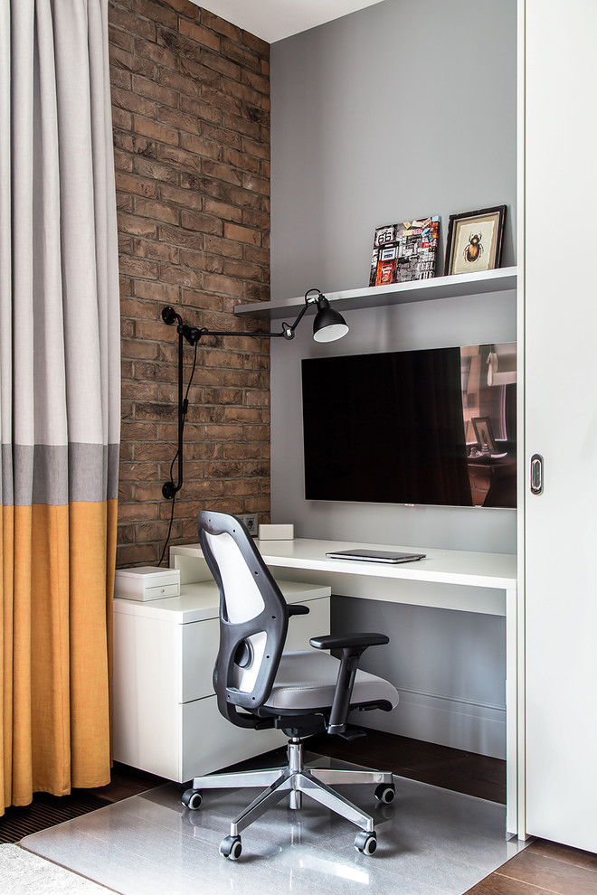 Réalisation d'un bureau design avec un mur gris, parquet foncé, un bureau intégré et un sol marron.