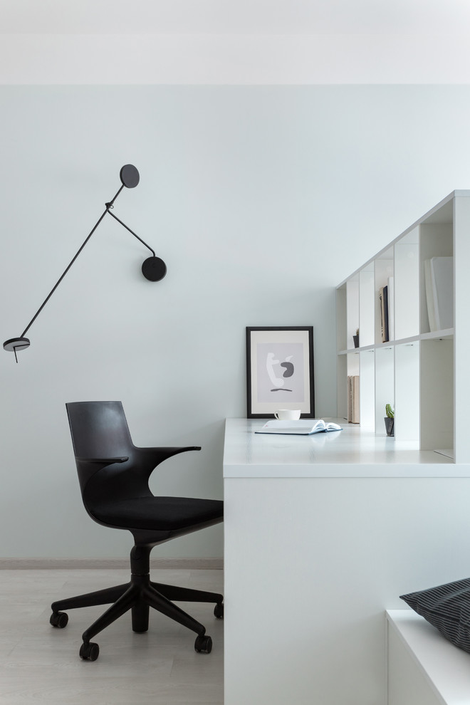 This is an example of a contemporary study in Moscow with white walls, a freestanding desk and beige floors.