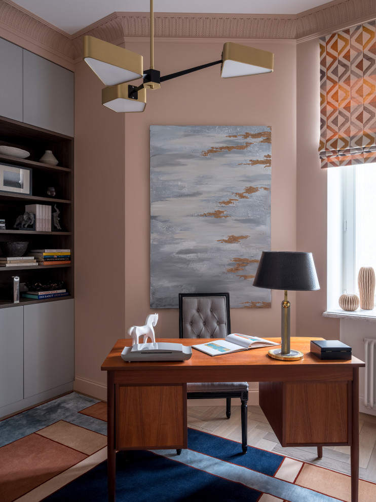 На фото: кабинет в стиле неоклассика (современная классика) с розовыми стенами, паркетным полом среднего тона, отдельно стоящим рабочим столом и коричневым полом