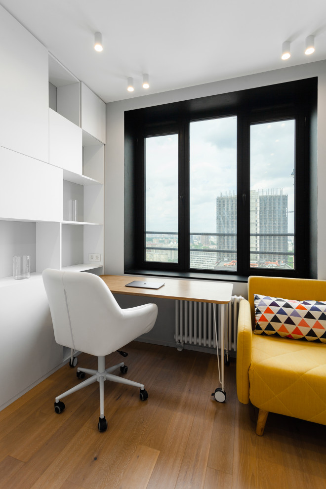 Imagen de despacho actual pequeño con paredes blancas, suelo laminado, escritorio independiente y suelo beige