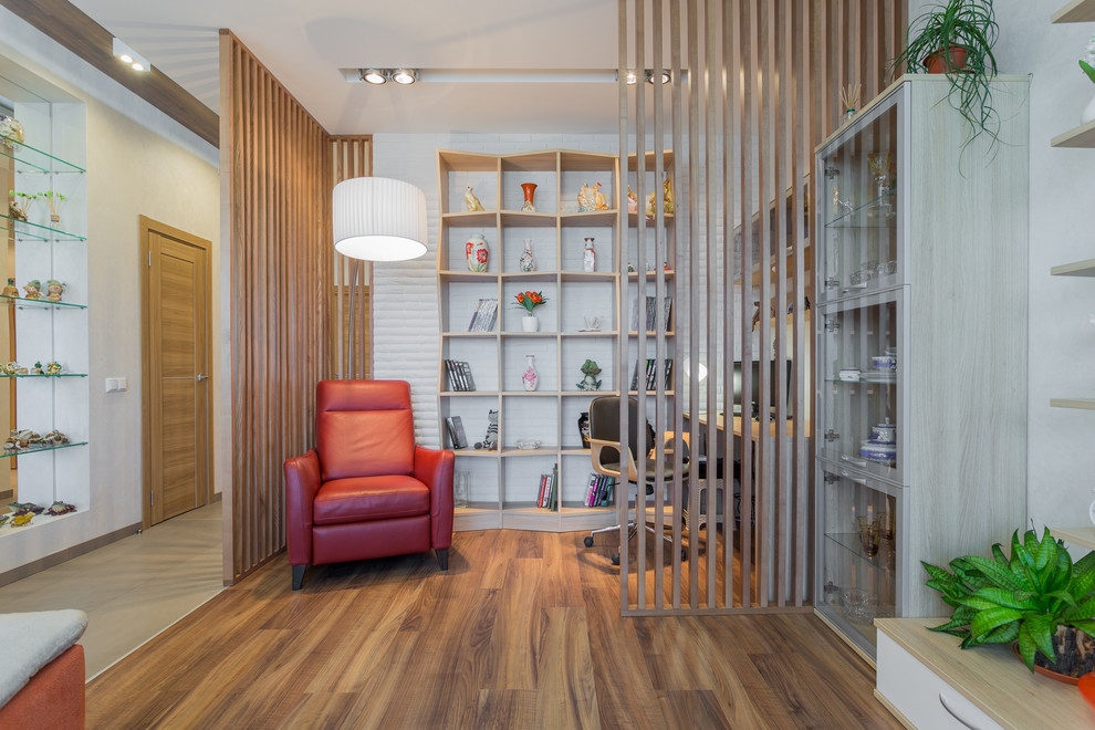 Modelo de despacho escandinavo de tamaño medio con paredes blancas, suelo de madera en tonos medios y escritorio independiente