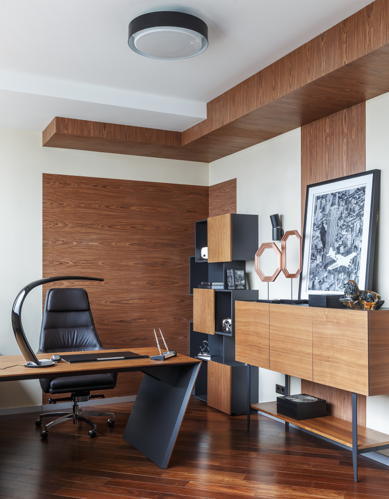 На фото: кабинет в современном стиле с белыми стенами, темным паркетным полом, отдельно стоящим рабочим столом и коричневым полом с