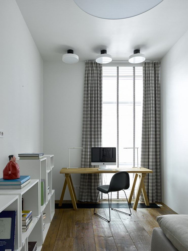 Aménagement d'un bureau contemporain avec un mur blanc, un sol en bois brun, un bureau indépendant et un sol marron.