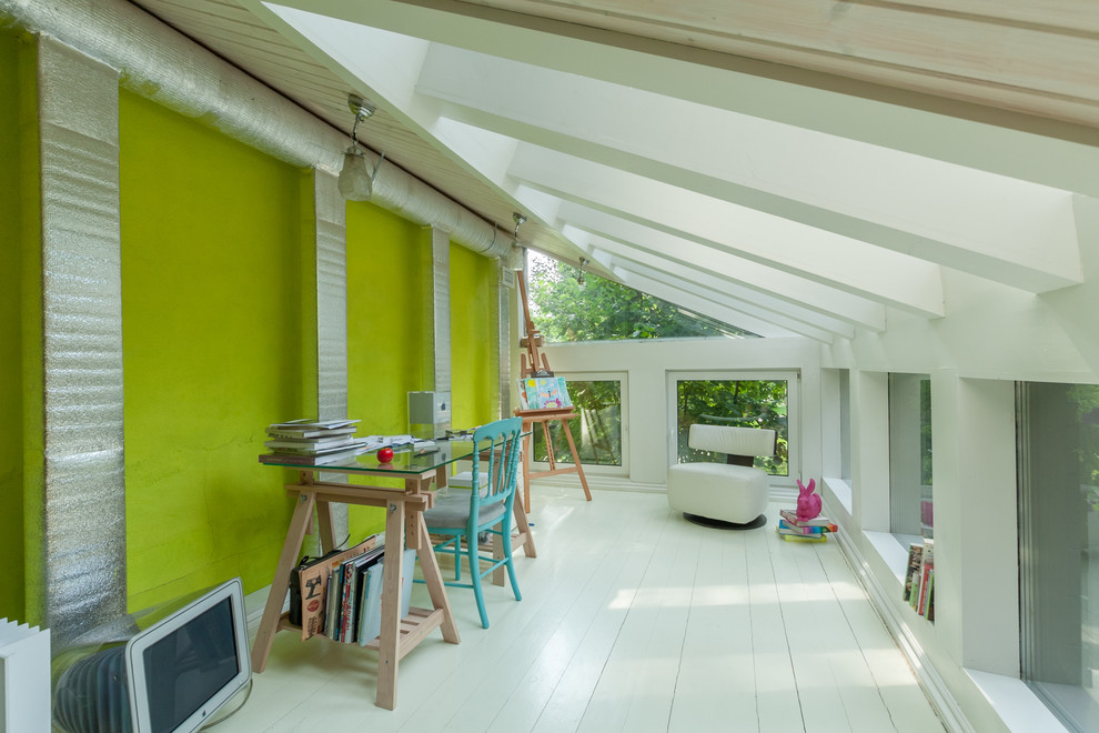 Imagen de estudio contemporáneo con paredes verdes, suelo de madera pintada y escritorio independiente