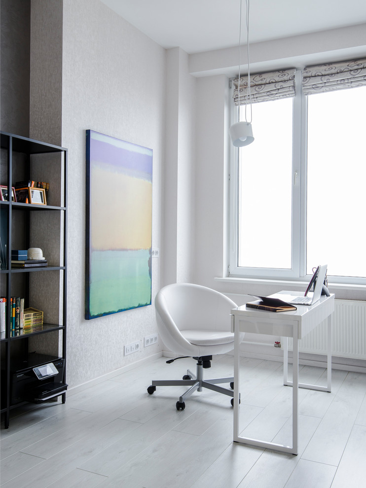 Ejemplo de despacho contemporáneo con paredes blancas, suelo de madera clara, escritorio independiente y suelo blanco