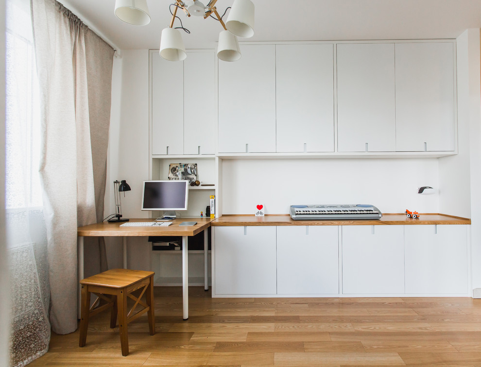 Imagen de despacho nórdico con paredes blancas, suelo de madera clara y escritorio empotrado