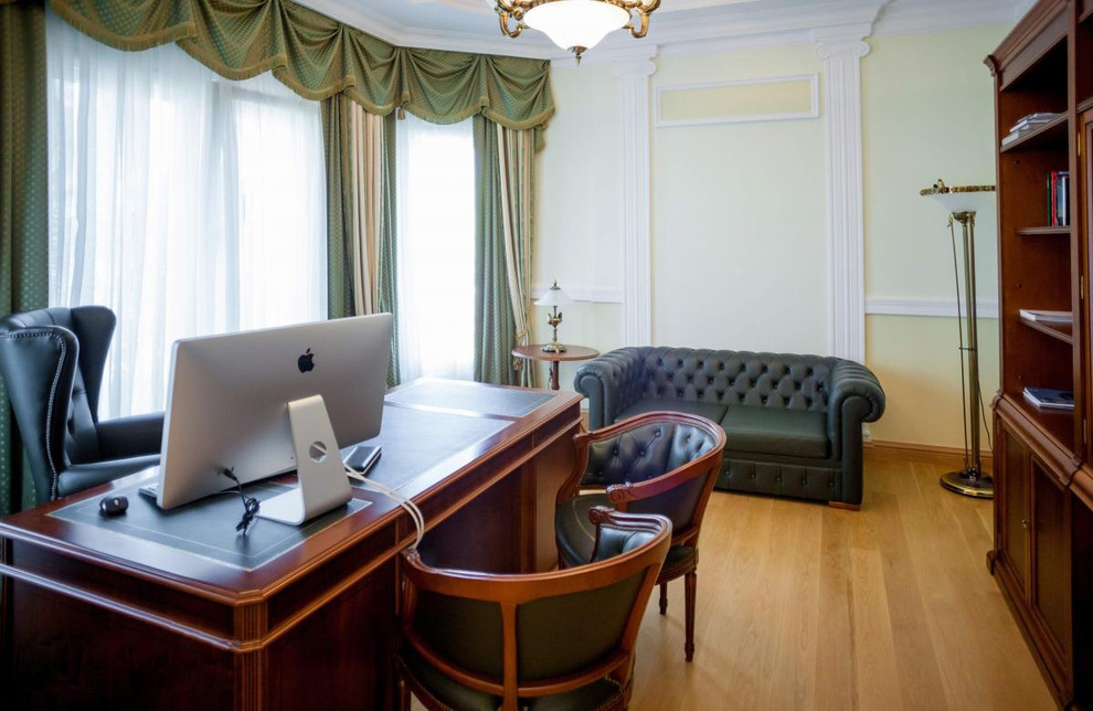 Foto de despacho tradicional de tamaño medio sin chimenea con paredes amarillas, suelo de madera en tonos medios y escritorio independiente