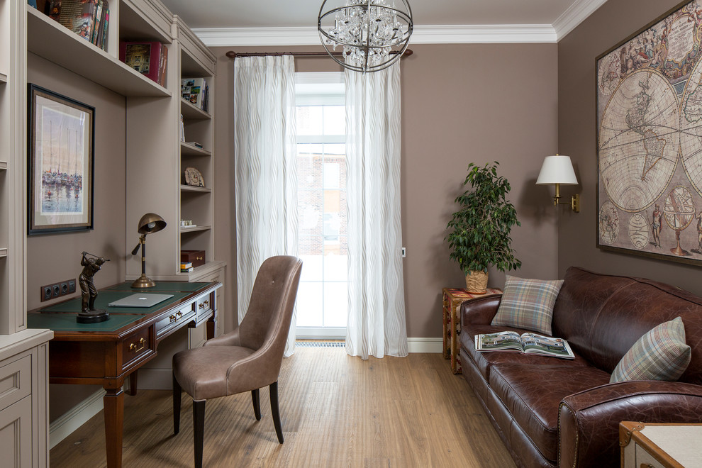 This is an example of a classic study in Moscow with brown walls, light hardwood flooring and a freestanding desk.
