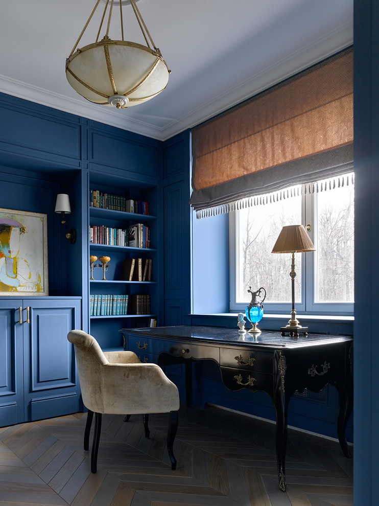 Inspiration för klassiska hemmabibliotek, med blå väggar, mellanmörkt trägolv, ett fristående skrivbord och flerfärgat golv