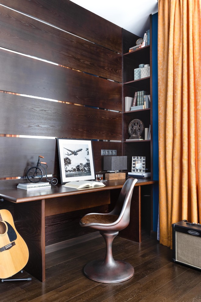 Modelo de despacho contemporáneo de tamaño medio con paredes azules, suelo de madera oscura, escritorio empotrado y suelo marrón