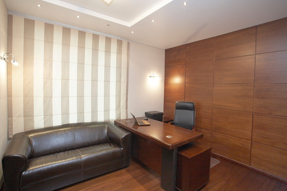 Ejemplo de despacho actual de tamaño medio sin chimenea con paredes beige, suelo de madera oscura y escritorio independiente