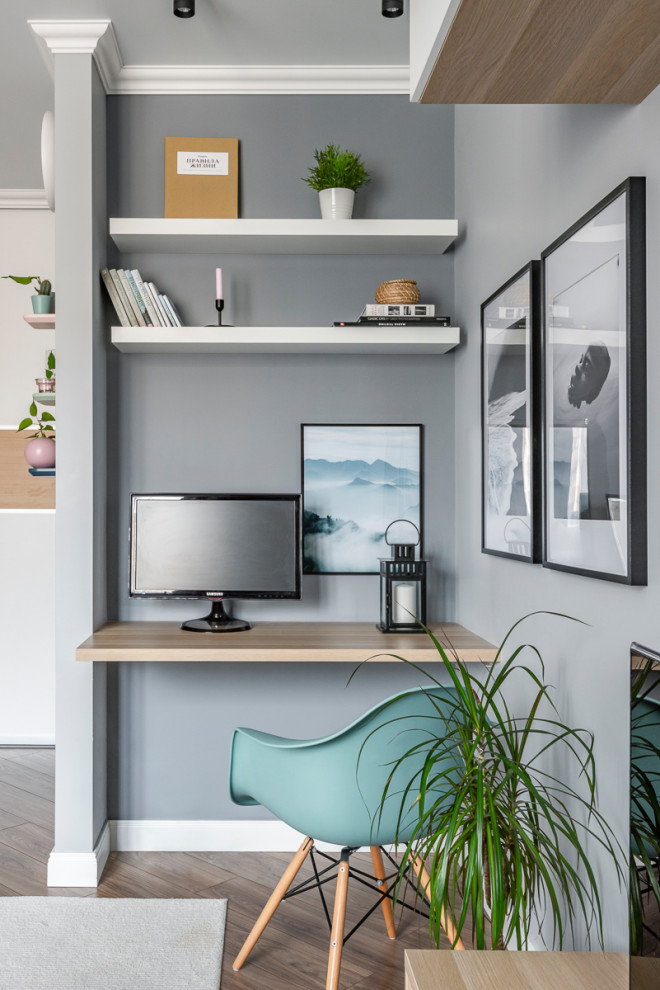 Nordisches Arbeitszimmer mit Arbeitsplatz, grauer Wandfarbe, braunem Holzboden, Einbau-Schreibtisch und braunem Boden in Sonstige