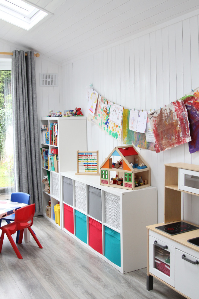 Immagine di una piccola cameretta per bambini da 1 a 3 anni moderna con pareti bianche, pavimento in laminato e pavimento grigio