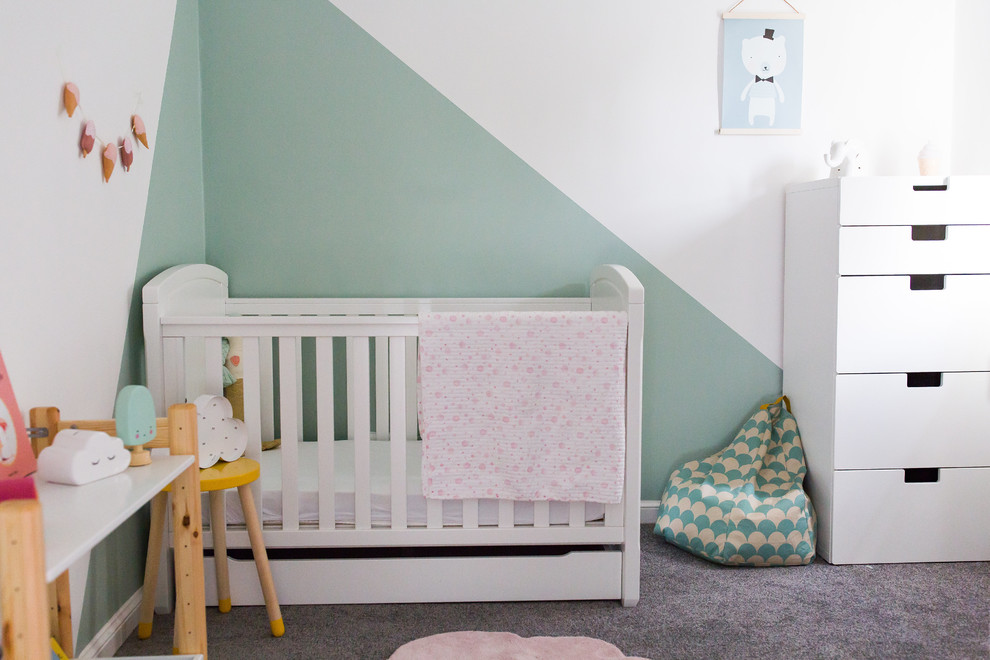 This is an example of a small scandinavian toddler’s room for girls in Surrey with green walls, carpet and grey floors.