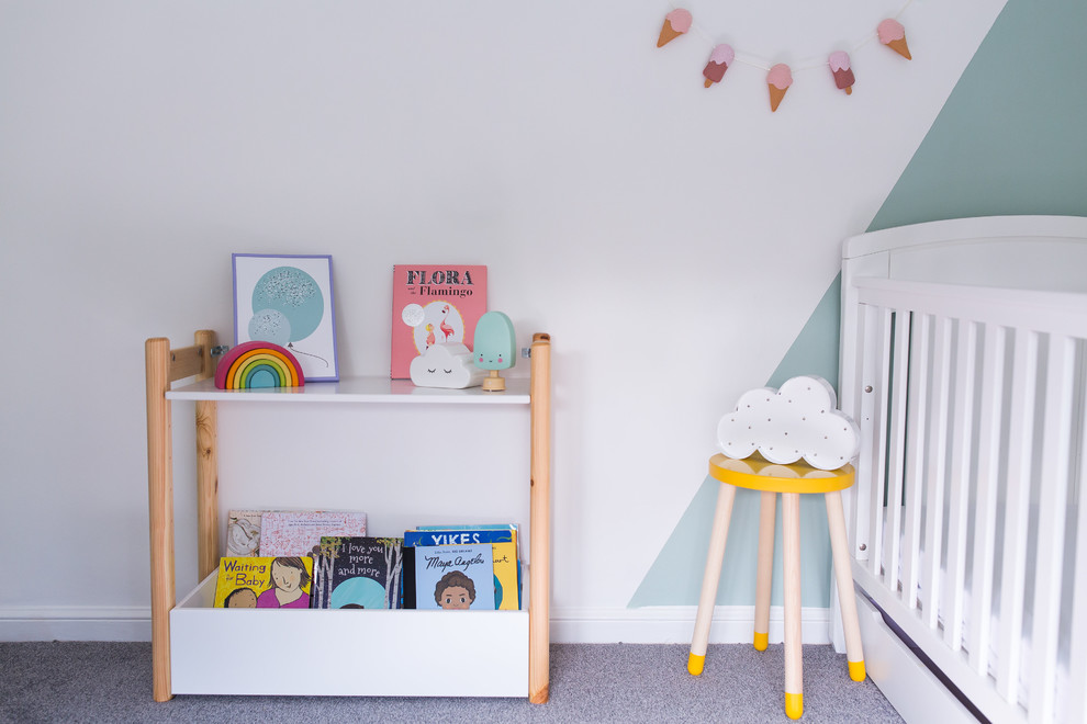 This is an example of a small scandi toddler’s room for girls in Surrey with green walls, carpet and grey floors.