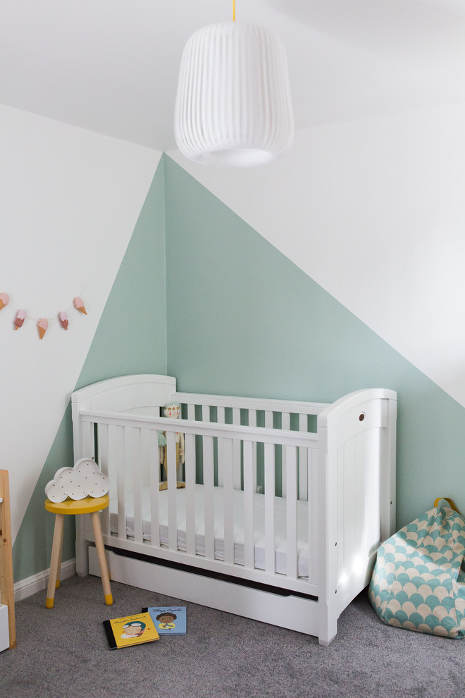 This is an example of a small scandinavian nursery for girls in Surrey with green walls, carpet and grey floors.