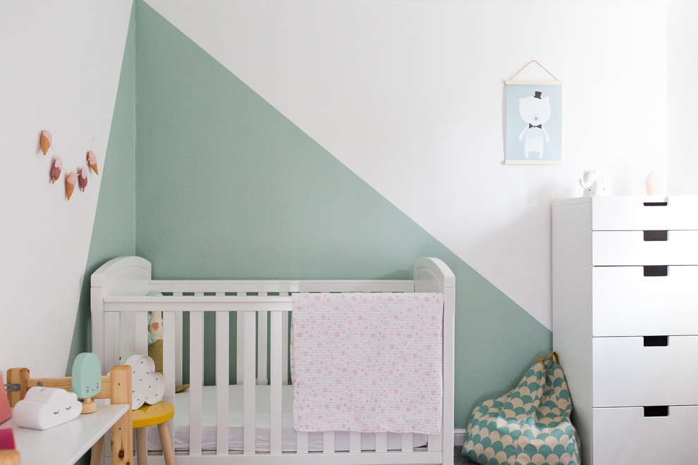 Imagen de habitación de bebé niña nórdica pequeña con paredes verdes, moqueta y suelo gris