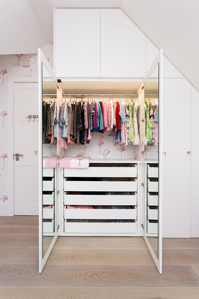 Photo of a contemporary kids' bedroom for girls in London with light hardwood flooring.