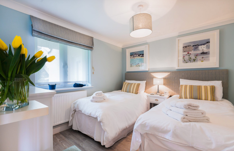 Example of a mid-sized beach style gender-neutral gray floor kids' bedroom design in Cornwall with blue walls