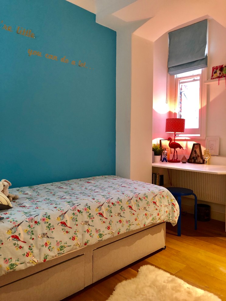 This is an example of a small contemporary teen’s room for girls in London with blue walls, medium hardwood flooring and brown floors.