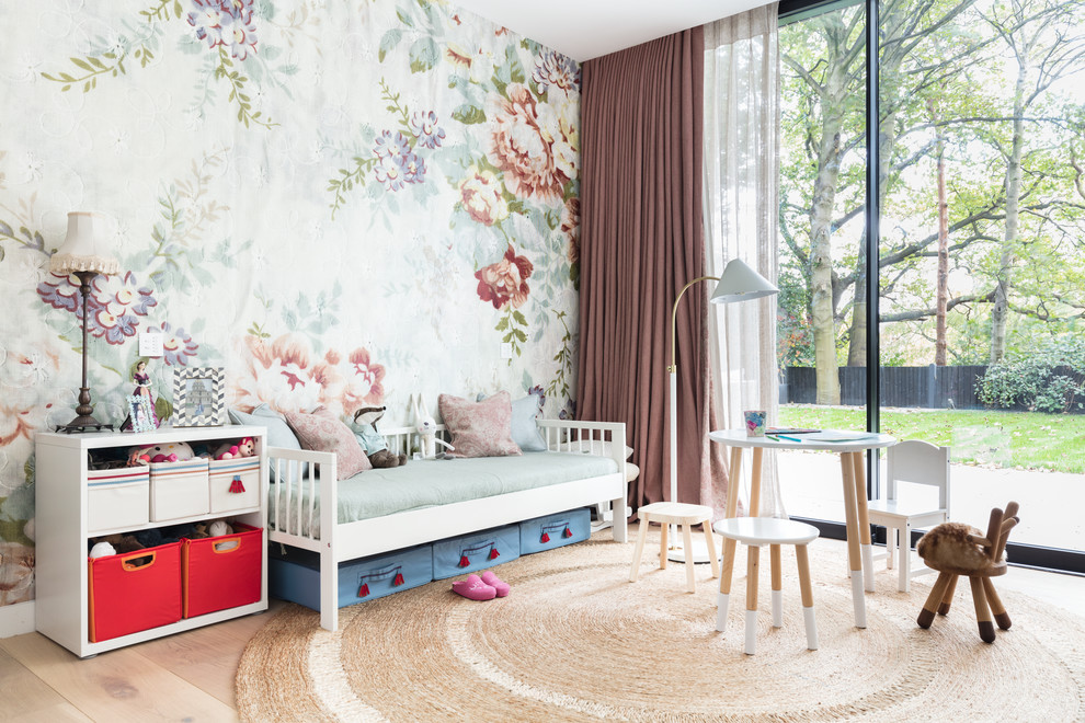 Scandinavian children’s room for girls in London with multi-coloured walls and light hardwood flooring.