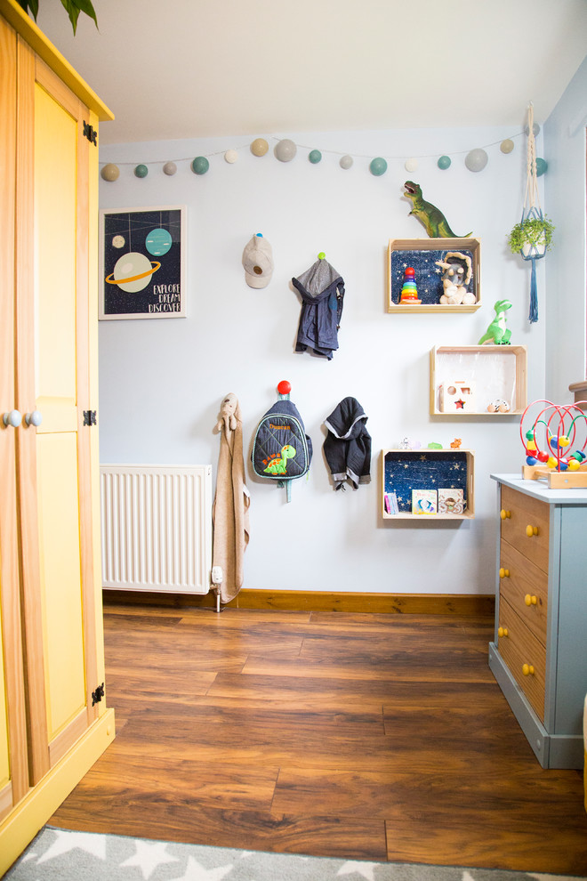 Immagine di una cameretta per bambini da 1 a 3 anni boho chic di medie dimensioni con pareti blu e pavimento in laminato