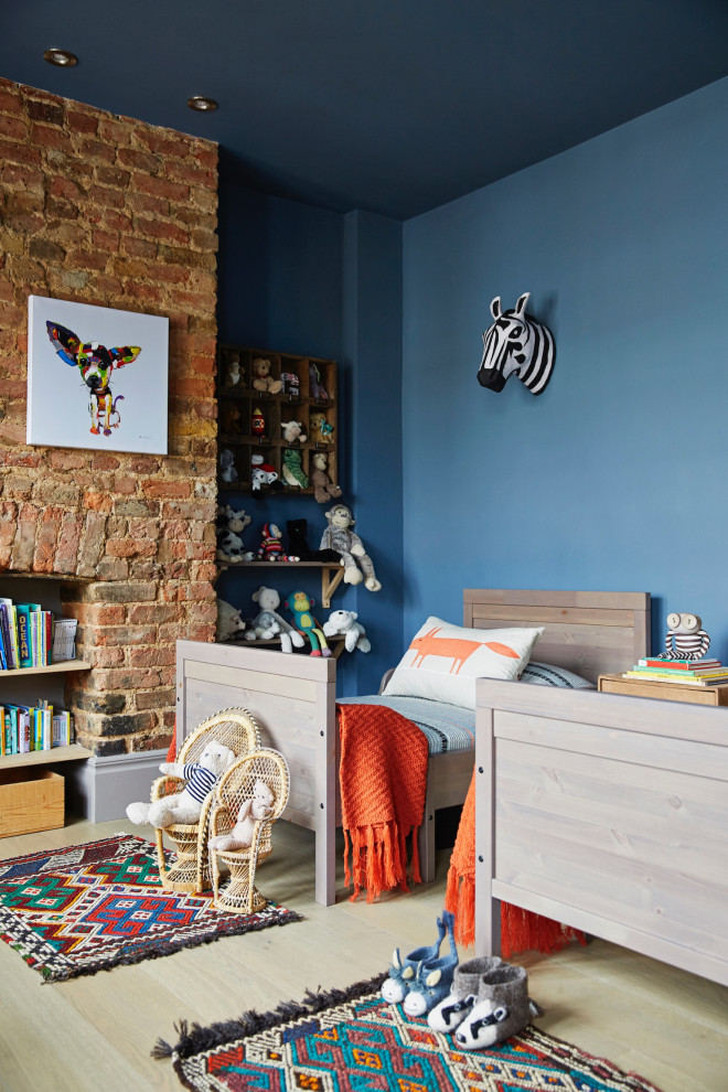 Réalisation d'une chambre d'enfant de 4 à 10 ans bohème avec un mur bleu, parquet clair et un mur en parement de brique.