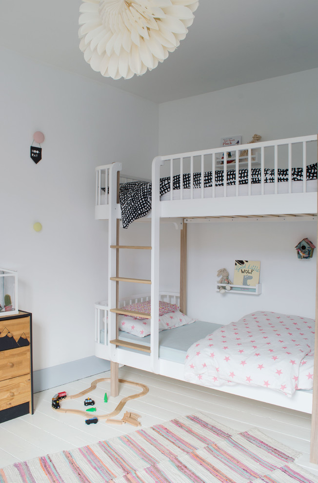 Foto på ett mellanstort skandinaviskt könsneutralt barnrum kombinerat med sovrum och för 4-10-åringar, med vita väggar och målat trägolv
