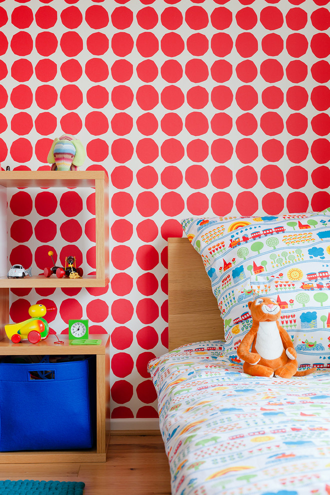 Inredning av ett modernt mellanstort könsneutralt barnrum kombinerat med sovrum och för 4-10-åringar, med ljust trägolv och röda väggar