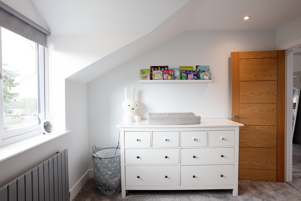 This is an example of a medium sized contemporary gender neutral toddler’s room in Berkshire with grey walls, carpet and grey floors.