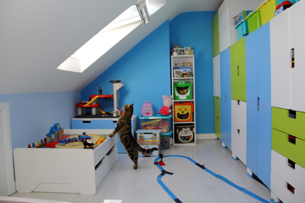 This is an example of a medium sized modern kids' bedroom for boys in London with blue walls and light hardwood flooring.