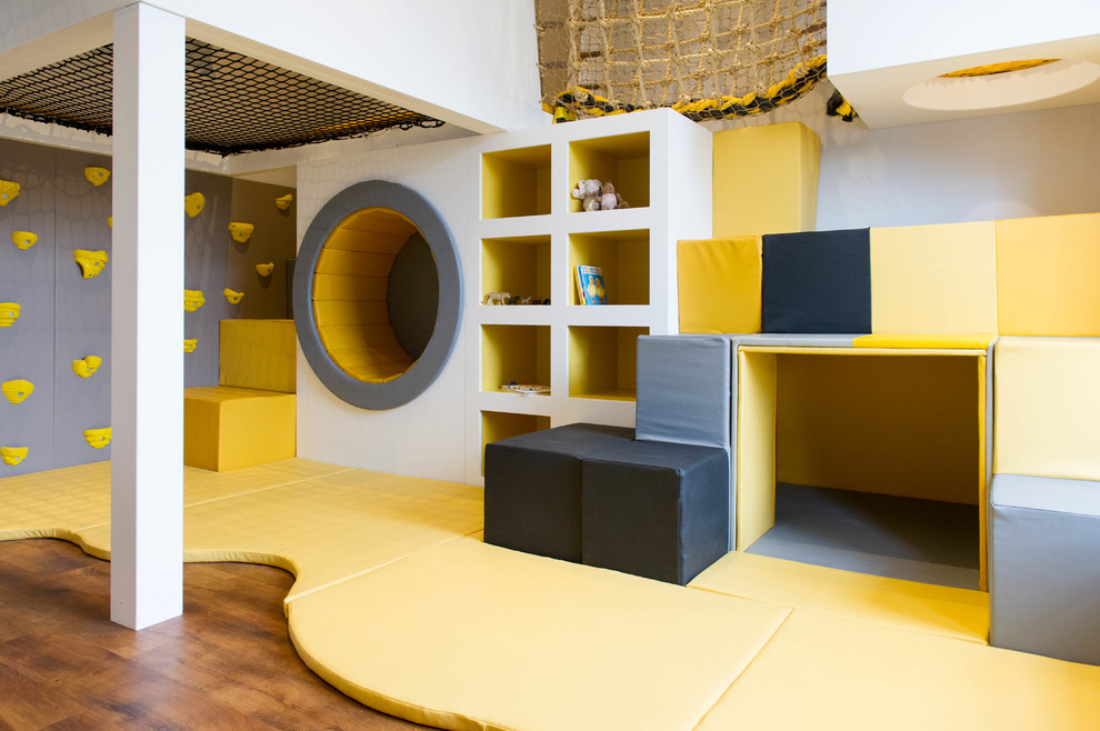 Exempel på ett modernt könsneutralt barnrum kombinerat med lekrum och för 4-10-åringar, med vita väggar, mellanmörkt trägolv och brunt golv