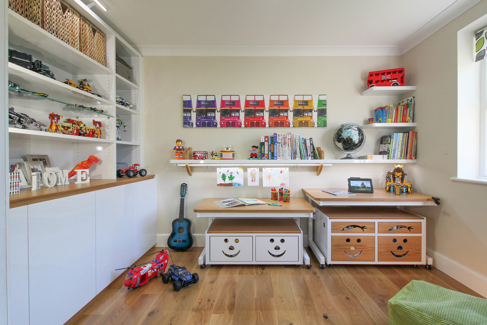 Contemporary gender neutral playroom in London with medium hardwood flooring and beige walls.