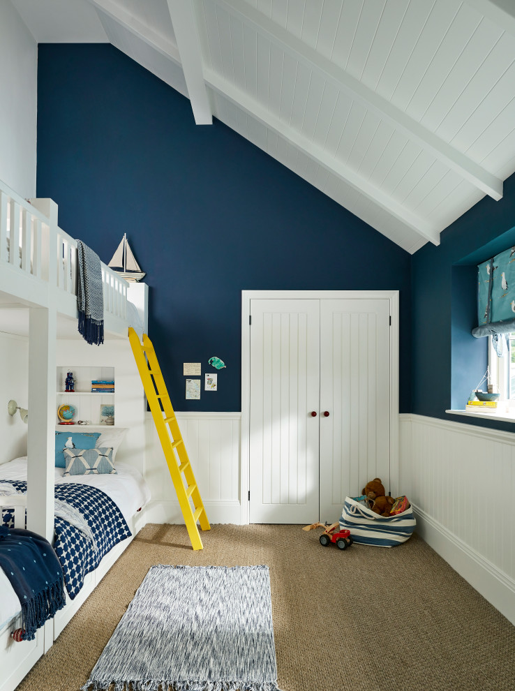 Aménagement d'une chambre d'enfant de 4 à 10 ans bord de mer avec un mur bleu, moquette, un sol marron, un plafond en lambris de bois, un plafond voûté et boiseries.