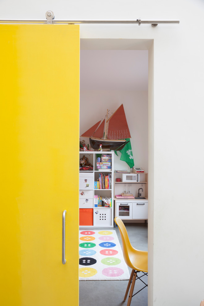 Bild på ett mellanstort funkis barnrum kombinerat med lekrum och för 4-10-åringar, med vita väggar, betonggolv och grått golv