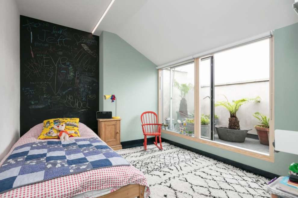 Example of a mid-sized minimalist gender-neutral kids' room design in London with green walls
