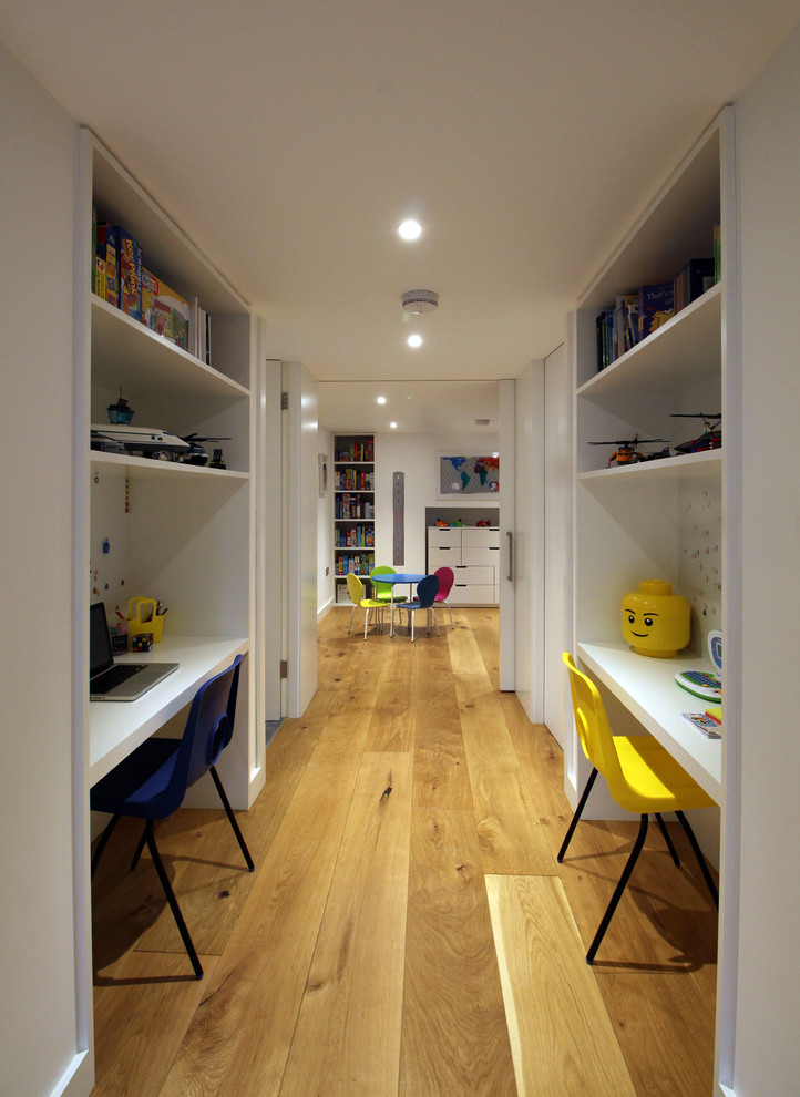 Idée de décoration pour une grande chambre neutre de 4 à 10 ans design avec un bureau, un mur blanc et parquet clair.