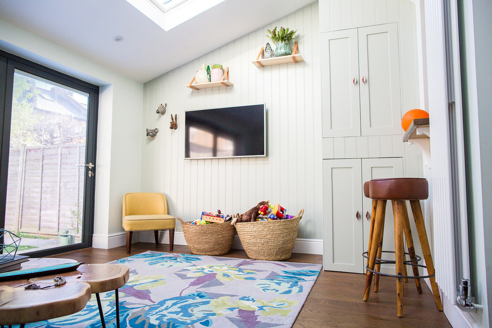 Rural gender neutral kids' bedroom in London with green walls, dark hardwood flooring and brown floors.